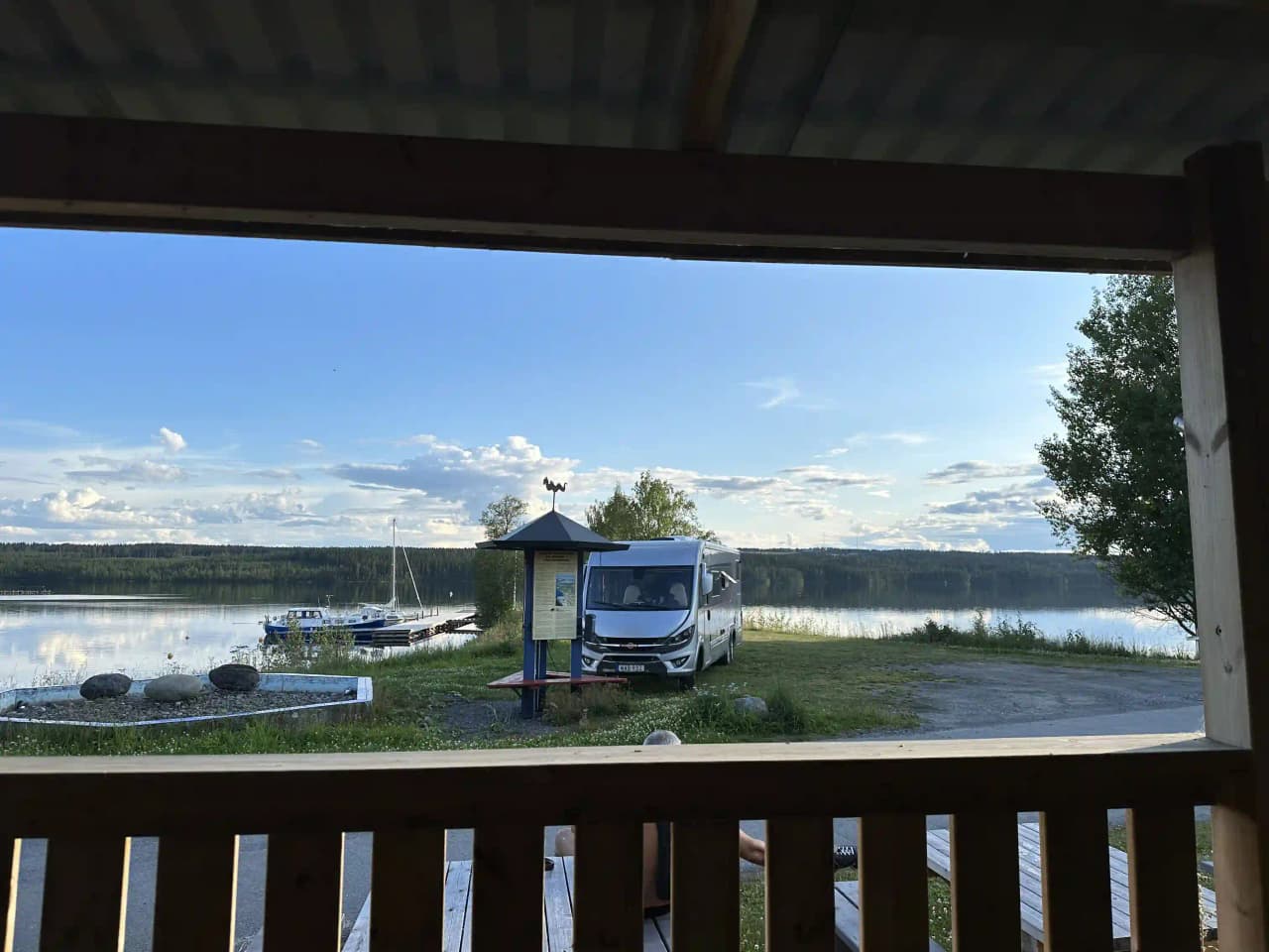 En bil parkerad framför Trångsvikens bygdegård, med flera olika fordonstyper synliga på parkeringen.