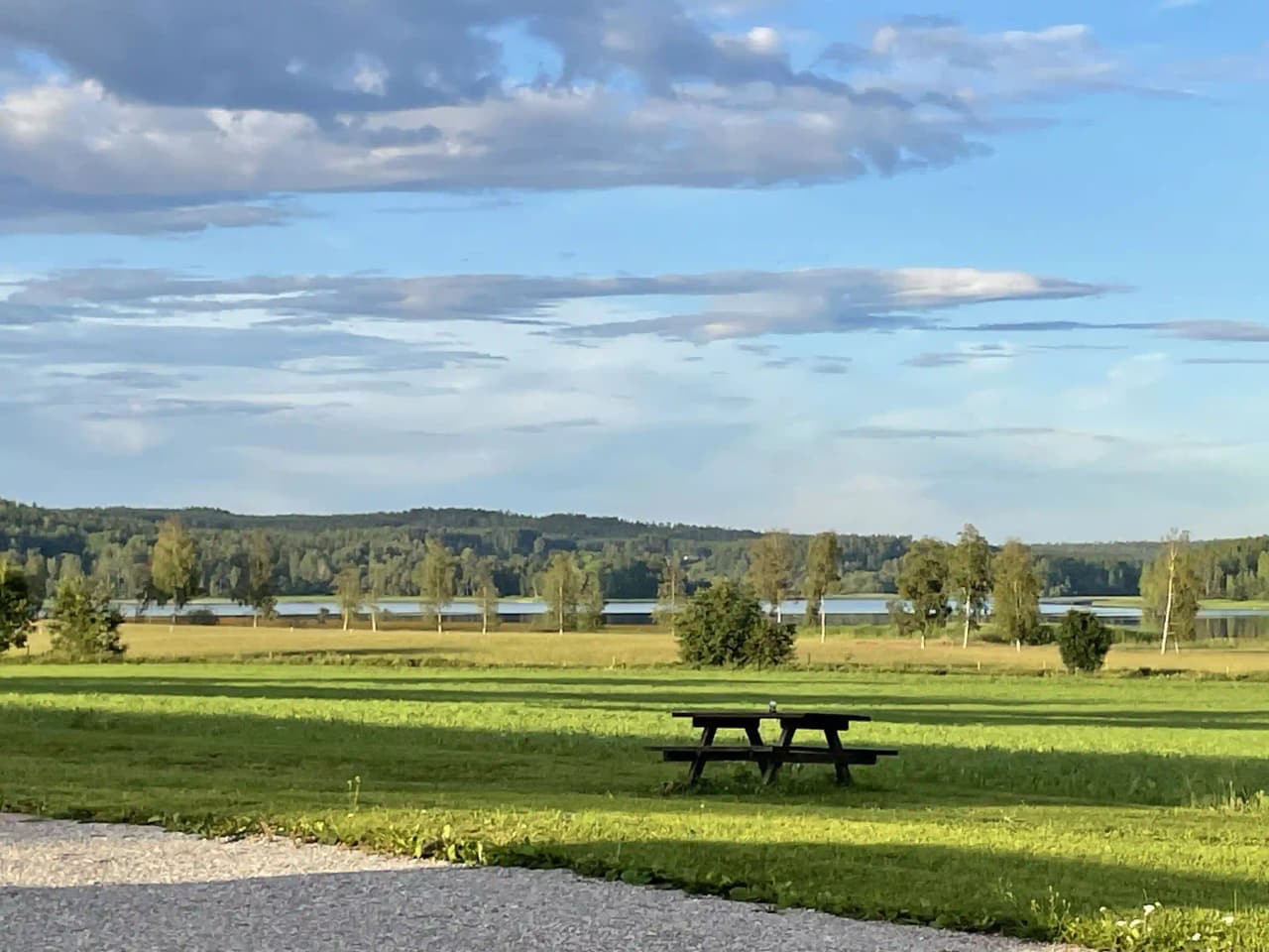 En vidsträckt gräsmark under en molnig himmel, med inslag av grönt och naturskönt landskap vid Älvsta Lodges.