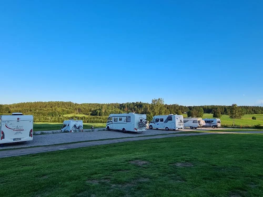 En husvagn står parkerad på en öppen plats under molnig himmel, omgiven av ett vidsträckt landskap.
