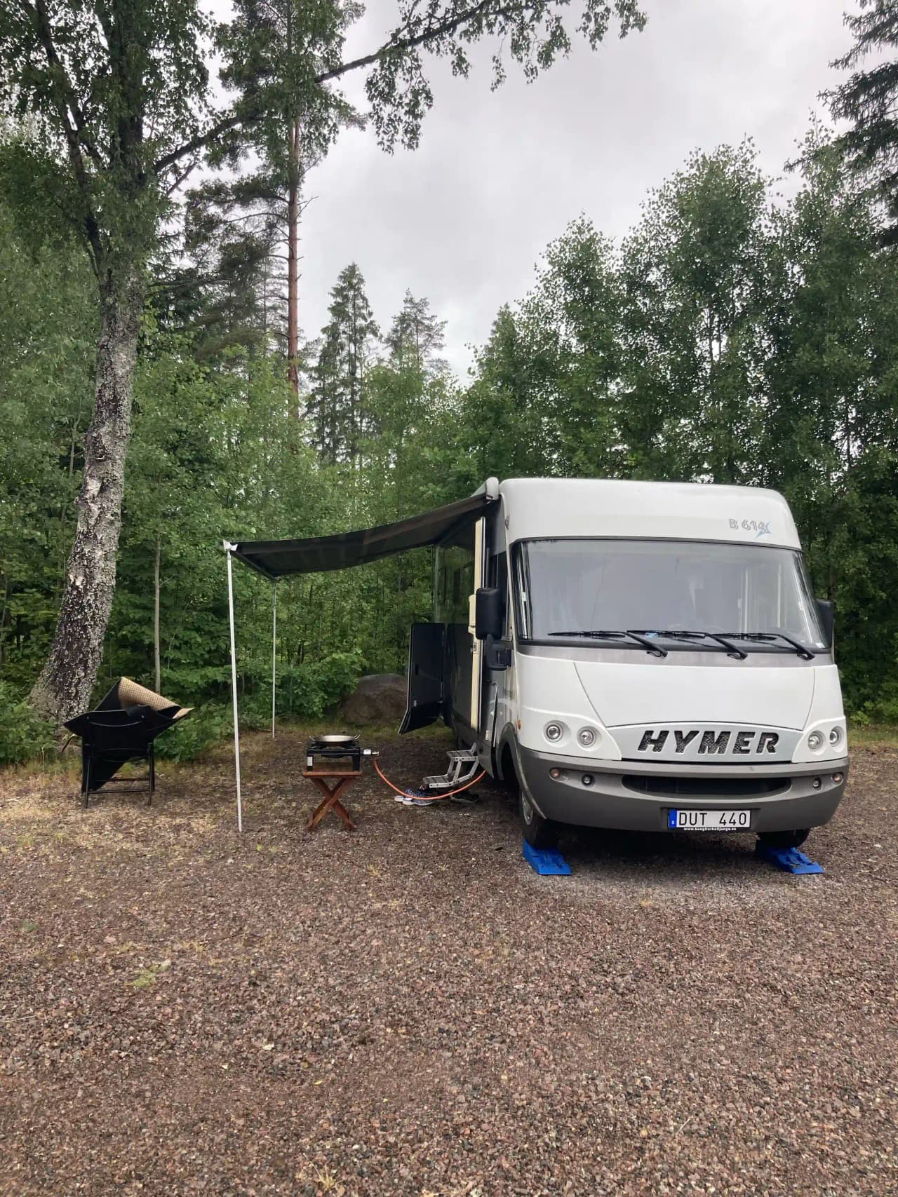 En husbil och en husvagn parkerade på en solig campingplats omgiven av grönska, vid Vimmerby Camping - Nossenbaden.