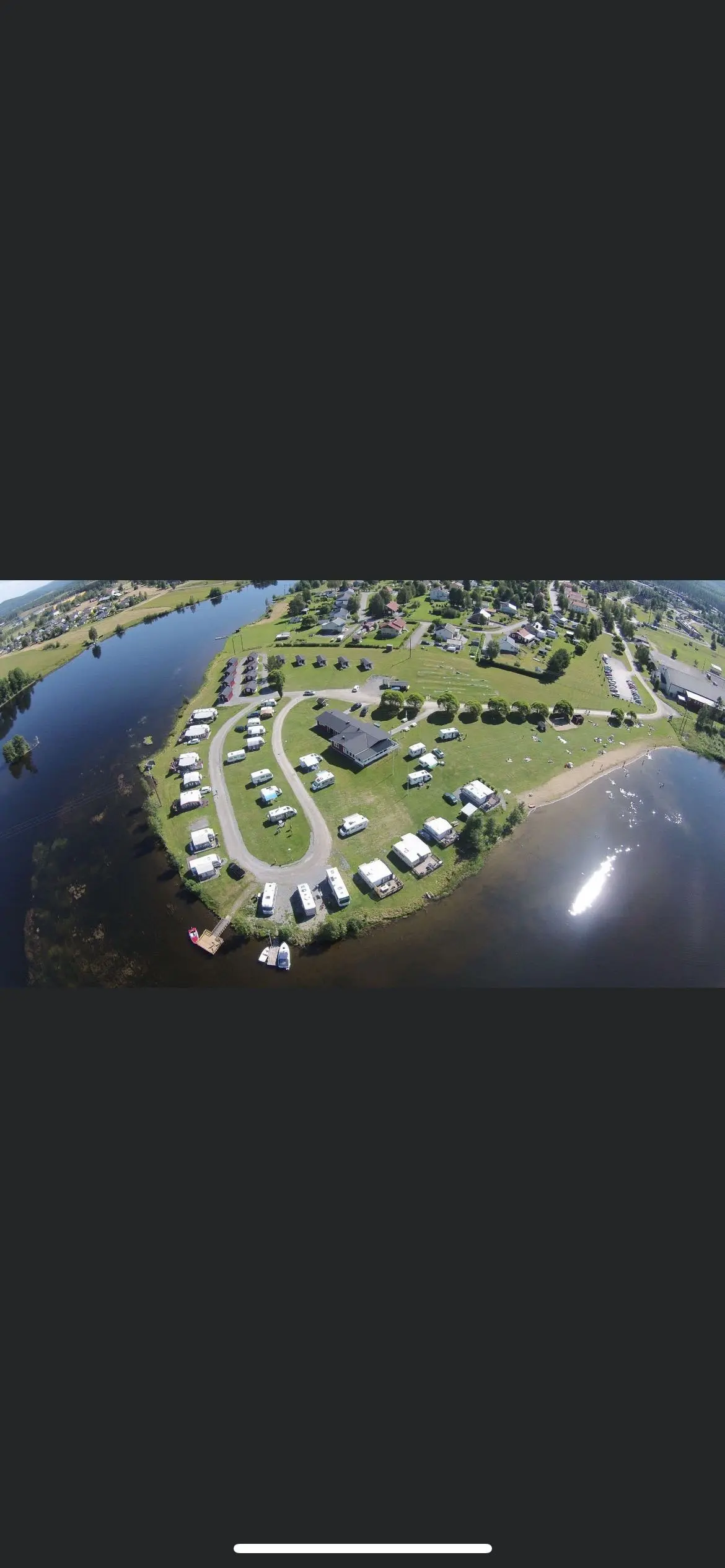 Flygbild över Långsele camping med en kustlinje, vattendrag och omgivande grönska.