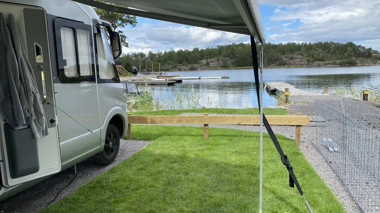 En bild av Eriksviks hamn med ett flertal fritidsfordon såsom husvagnar och husbilar uppställda i närheten av vattnet. I bakgrunden syns en blandning av naturlig omgivning och hamnens infrastruktur.