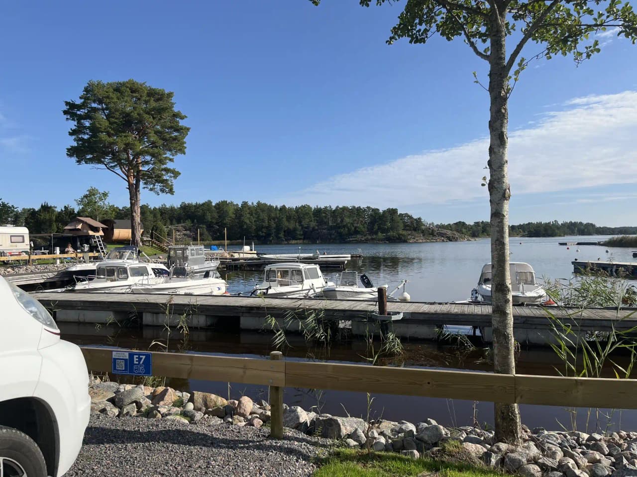 En bild av Eriksviks hamn med flera båtar förtöjda vid kajen. Vattnet är lugnt och omges av en småbåtshamn med bryggor.