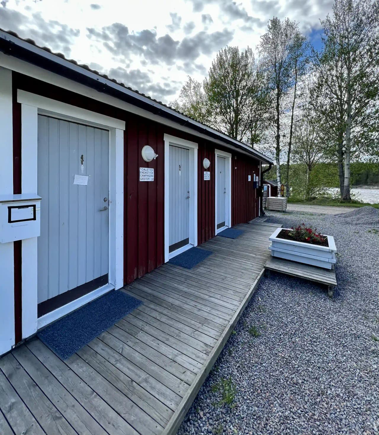 En träbyggnad ses på Kamlunge camping, omgiven av frysta landskap. Byggnaden har träpaneler, vilket skapar en rustik atmosfär.