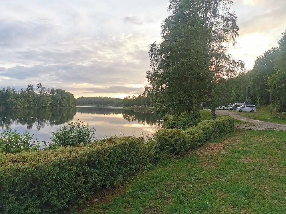 En lugn och naturskön vattenmassa omgiven av grönska vid Ljuvadal camping & ställplats, perfekt för avkopplande friluftsaktiviteter.