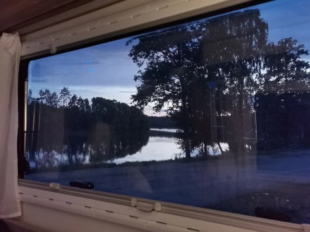 En glasskiosk reflekterar solens ljus, omgiven av skira gardiner, på Ljuvadal Camping & Ställplats.