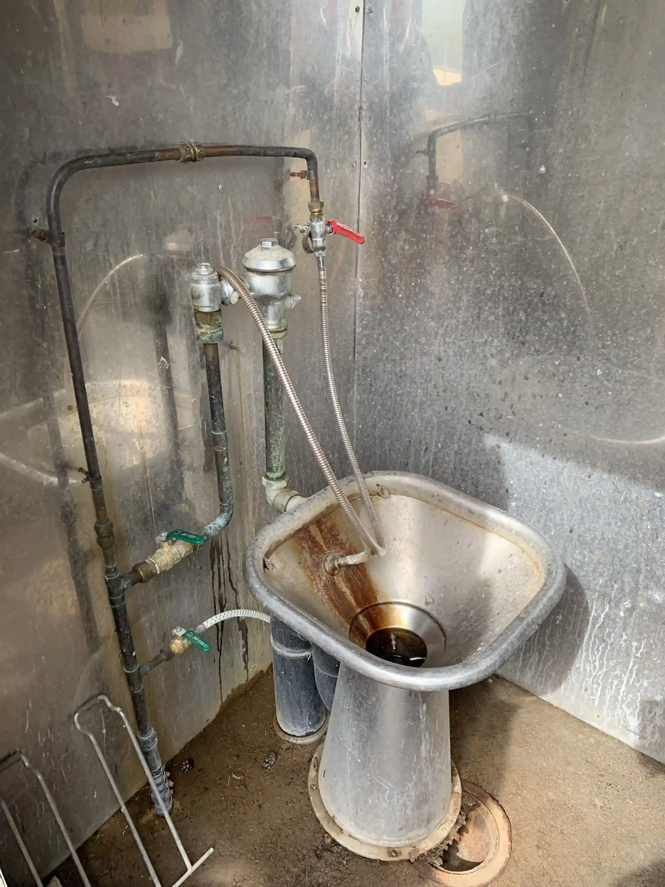 En närbild av ett rörsystem i metall vid Sandnäsets Bad & Camping, omgiven av kablar och andra VVS-element.