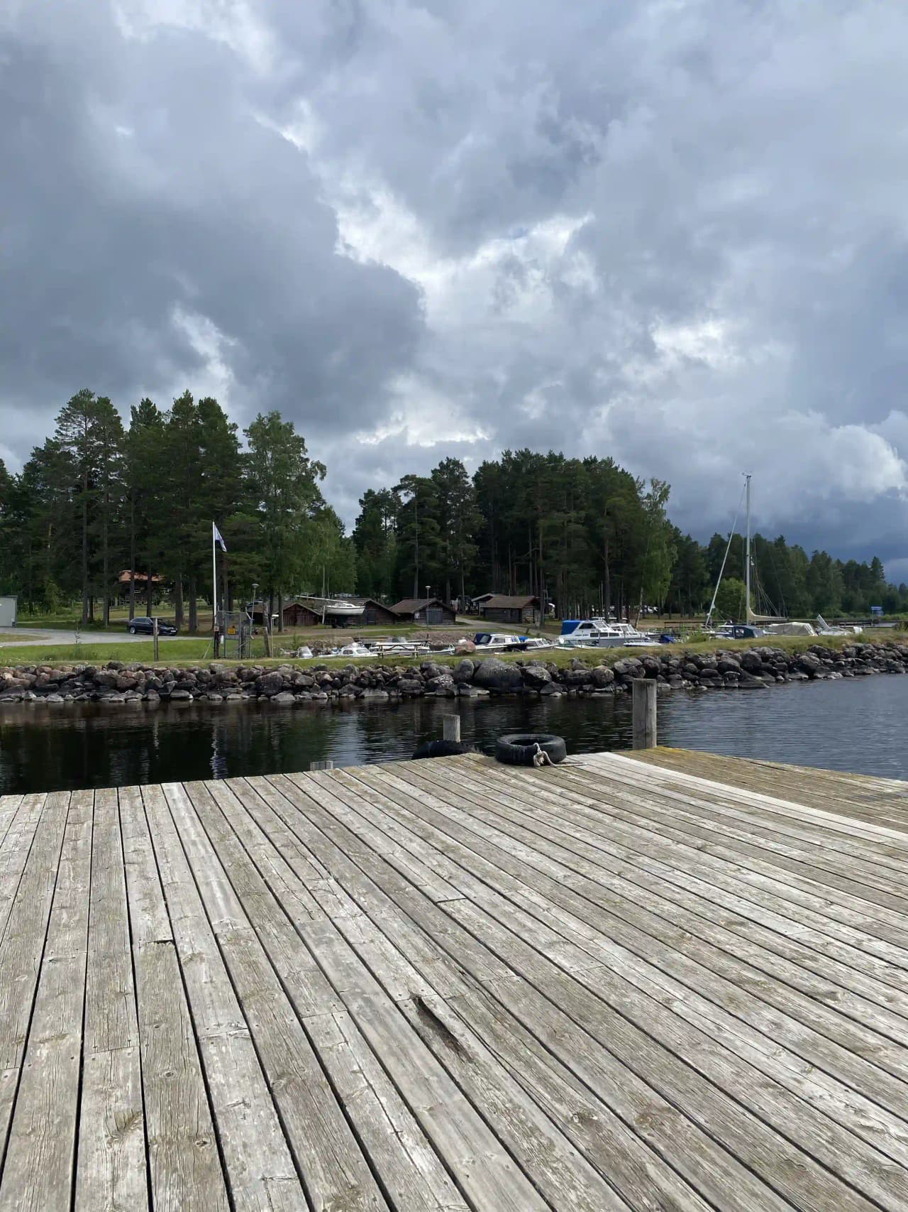 En träbrygga med gångväg vid Tällbergs camping, omgiven av naturlig miljö och grönska.