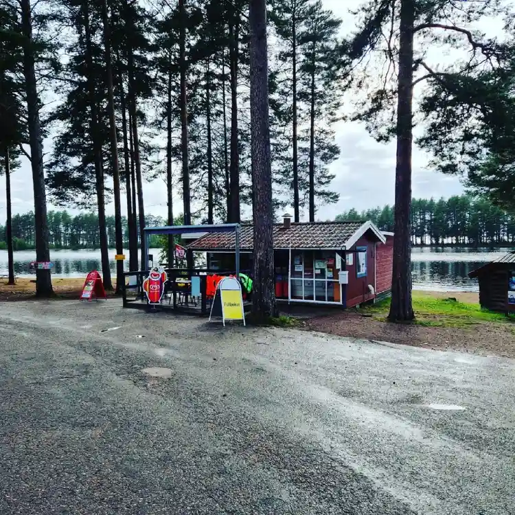 En pittoresk campingplats vid en sjö med stilla vatten och omgivande grönska i Tällberg.