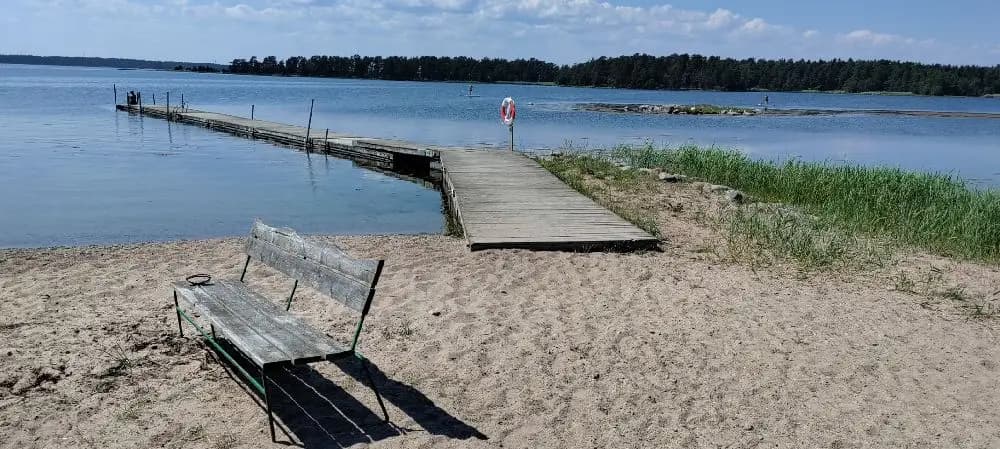 Bild av Kaffetorpets camping som ligger vid en fridfull sjö, omgiven av grönska. En lång kustlinje sträcker sig längs vattenbrynet, vilket skapar en naturskön och rogivande atmosfär.