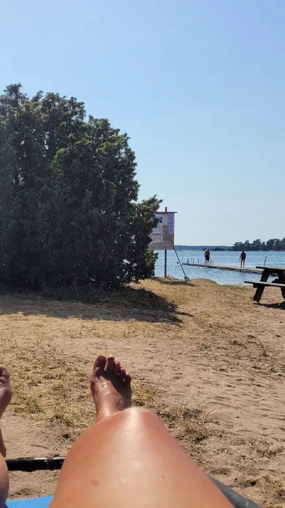 En strandmiljö med sommarkänsla på Kaffetorpets Camping. Solstolar står utplacerade på sanden nära havet, medan glada campare njuter av sol och bad.
