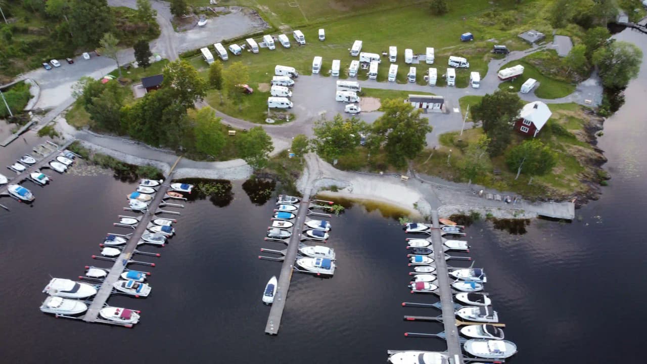 Bild på Upperuds Gästhamn med båtar förtöjda vid en brygga. Hamnen är omgiven av lugnt vatten och skogsklädda stränder i bakgrunden.