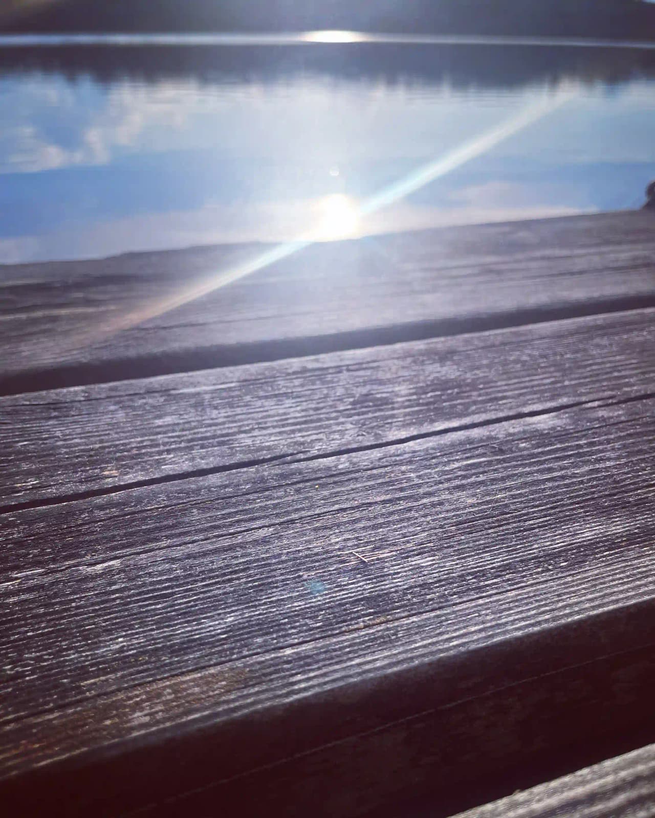 Bild av Upperuds Gästhamn i solnedgången, med horisonten i blåa nyanser och solens strålar som skapar ett ljusspel över himlen.