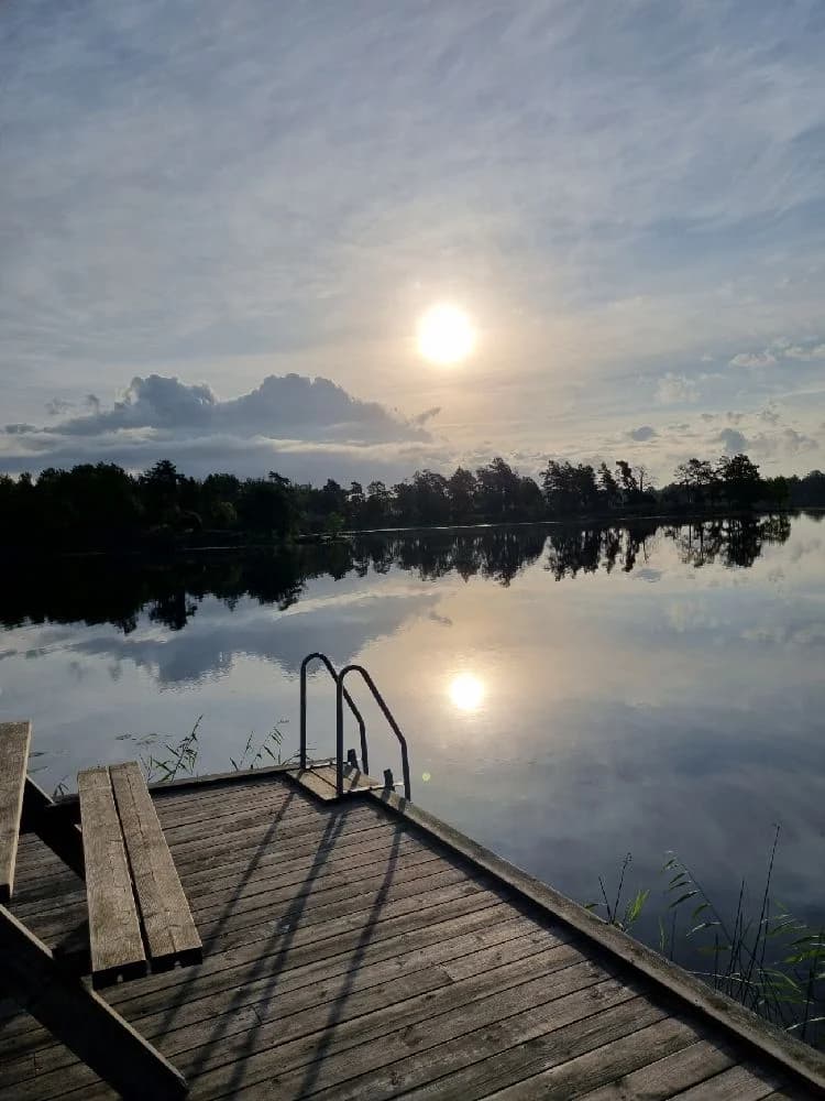 En vacker solnedgång vid Upperuds Gästhamn med spegelblankt vatten och en klar himmel i bakgrunden, där kvällsljuset reflekteras i ytan och skapar en rofylld och naturskön atmosfär.