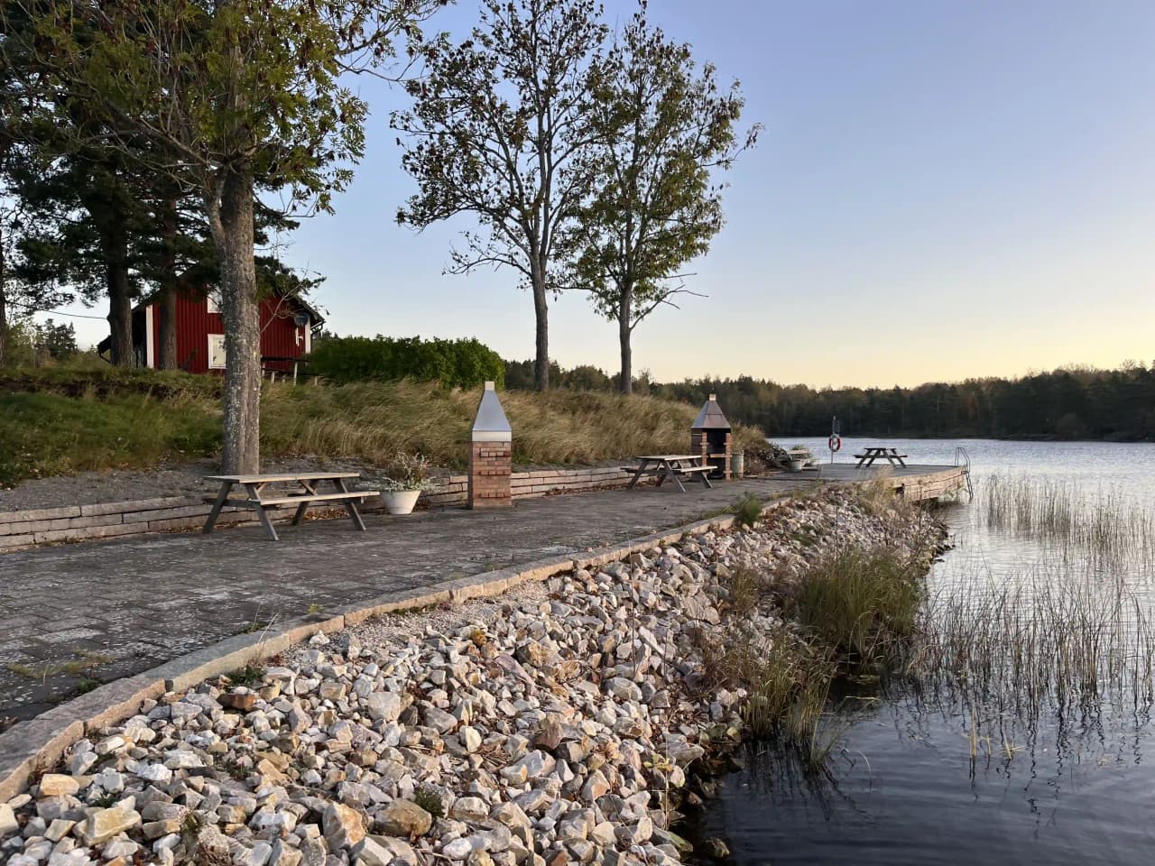 Vy över Upperuds Gästhamn med en stilla vattenyta omgiven av gröna strandkanter. Båtar ligger förtöjda längs bryggan medan den omgivande naturen speglas i vattnet.