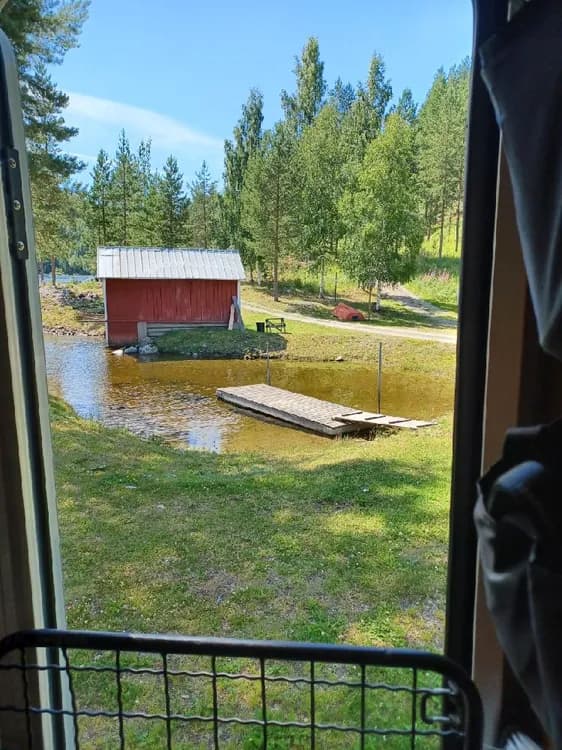 En bild av ett timmerhus i en trädgårdsmiljö på Zorbcenter, med en bakgård som ger en inbjudande och naturnära atmosfär.