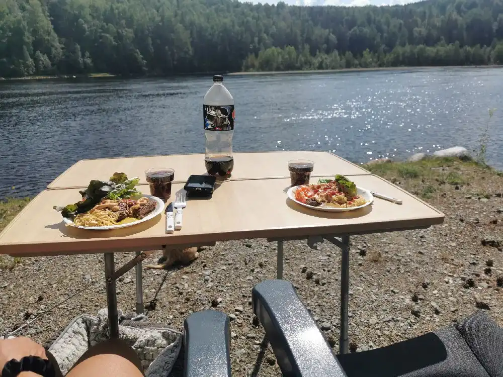 Utomhusdukning med frukostservering på Zorbcenter, inklusive tallrikar, glas och bestick på ett trämöblemang.
