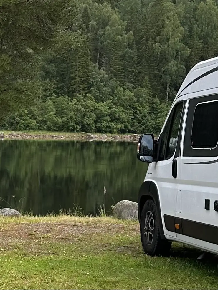 En vit företagsbil parkerad på en grön gräsyta vid Zorbcenter, reflekterande soljus i vindrutan.