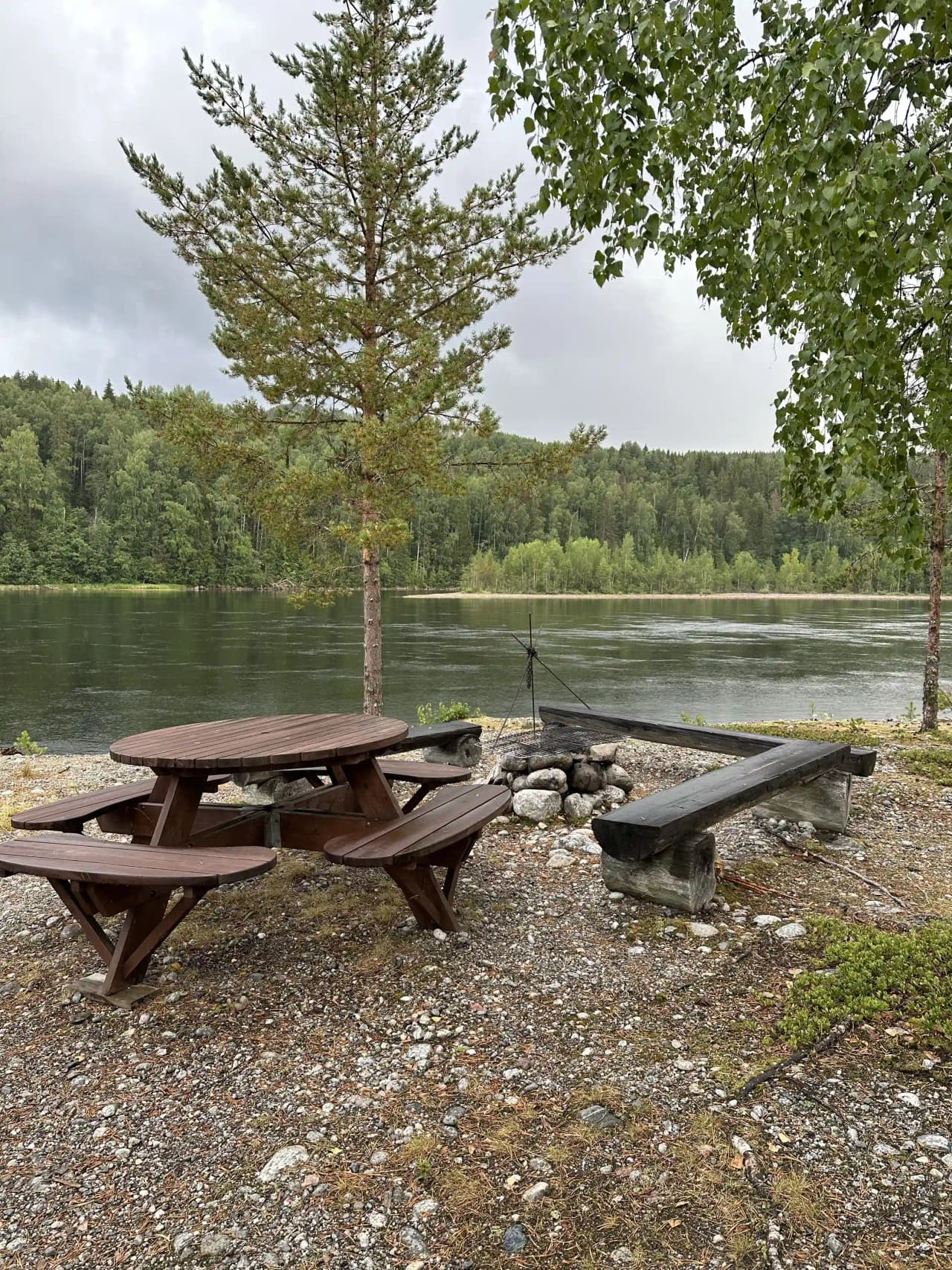 En picknickbänk med utsikt över en sjö, omgiven av grönskande parkmiljö på Zorbcenter.