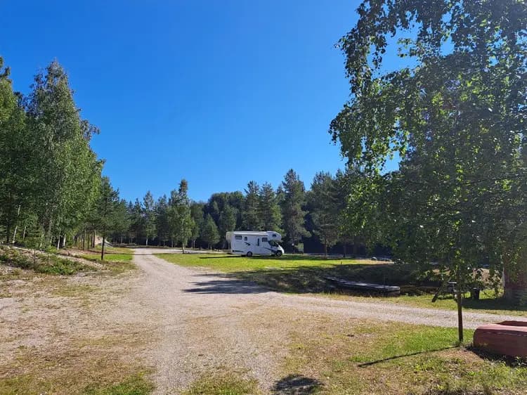 En öppen fält med träd och en husvagn vid en grusväg på Zorbcenter.