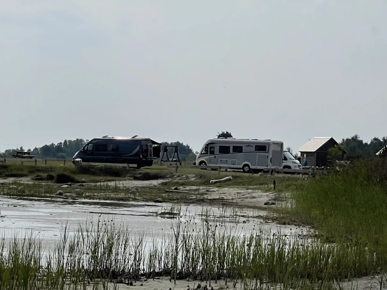 Vy över Wikegårds semesterby & ställplatscamping med husbilar och husvagnar parkerade på en campingplats omgiven av grönska och våtmarker.