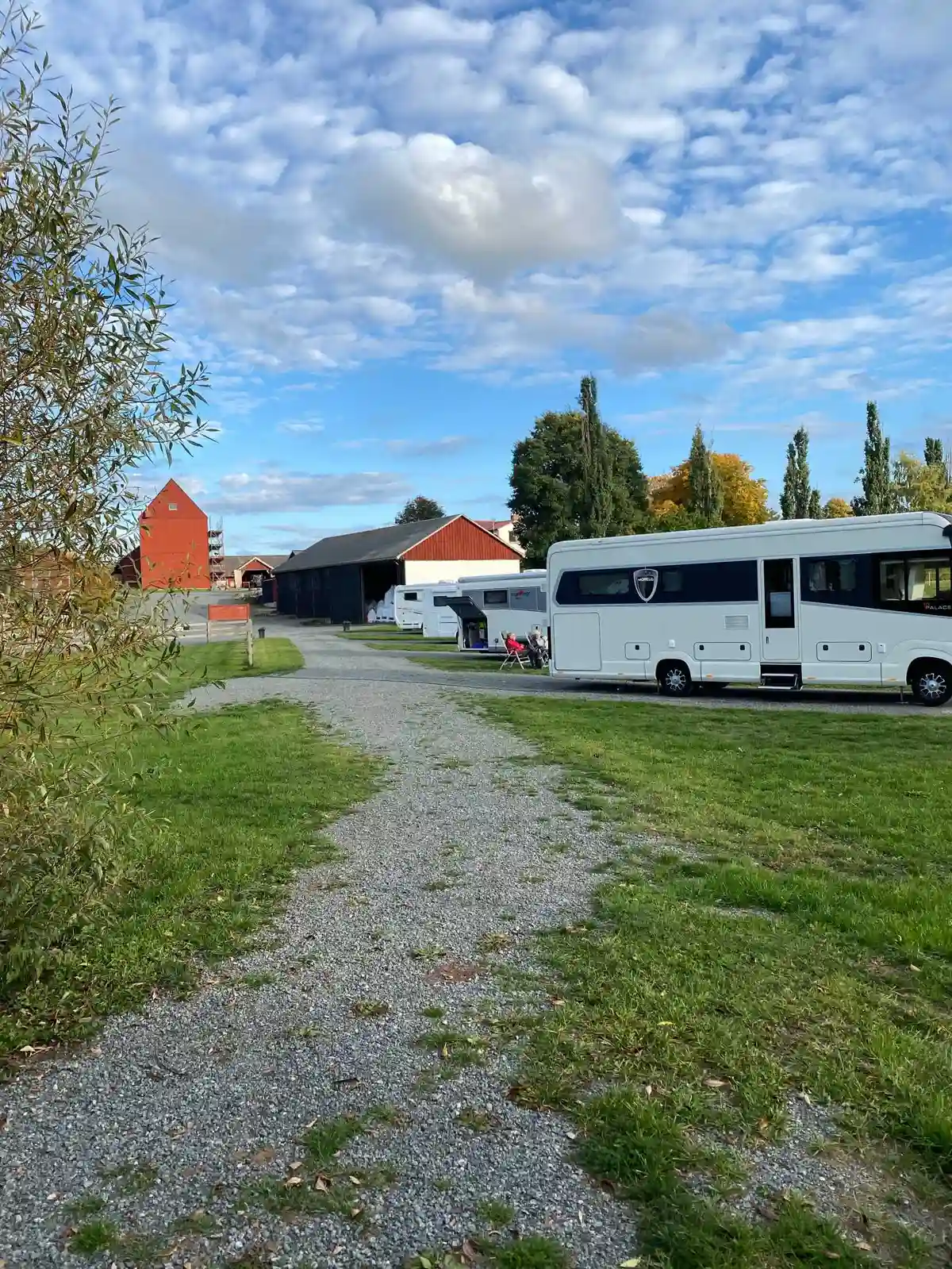 En parkeringsplats vid Kedumsvik ställplats, med flera bilar och husbilar parkerade längs en grusad uppfart.