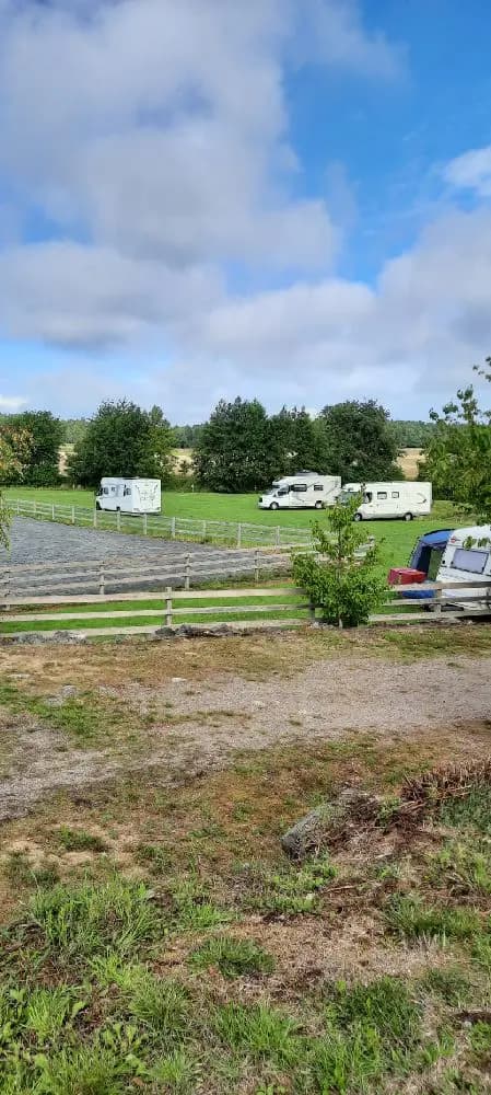 En vidsträckt gräsyta under en molnig himmel vid Kedumsvik ställplats.