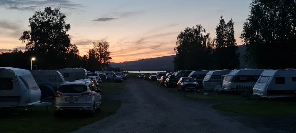 En husbil parkerad vid en campingplats under skymning, omgiven av stilla kvällsljus.