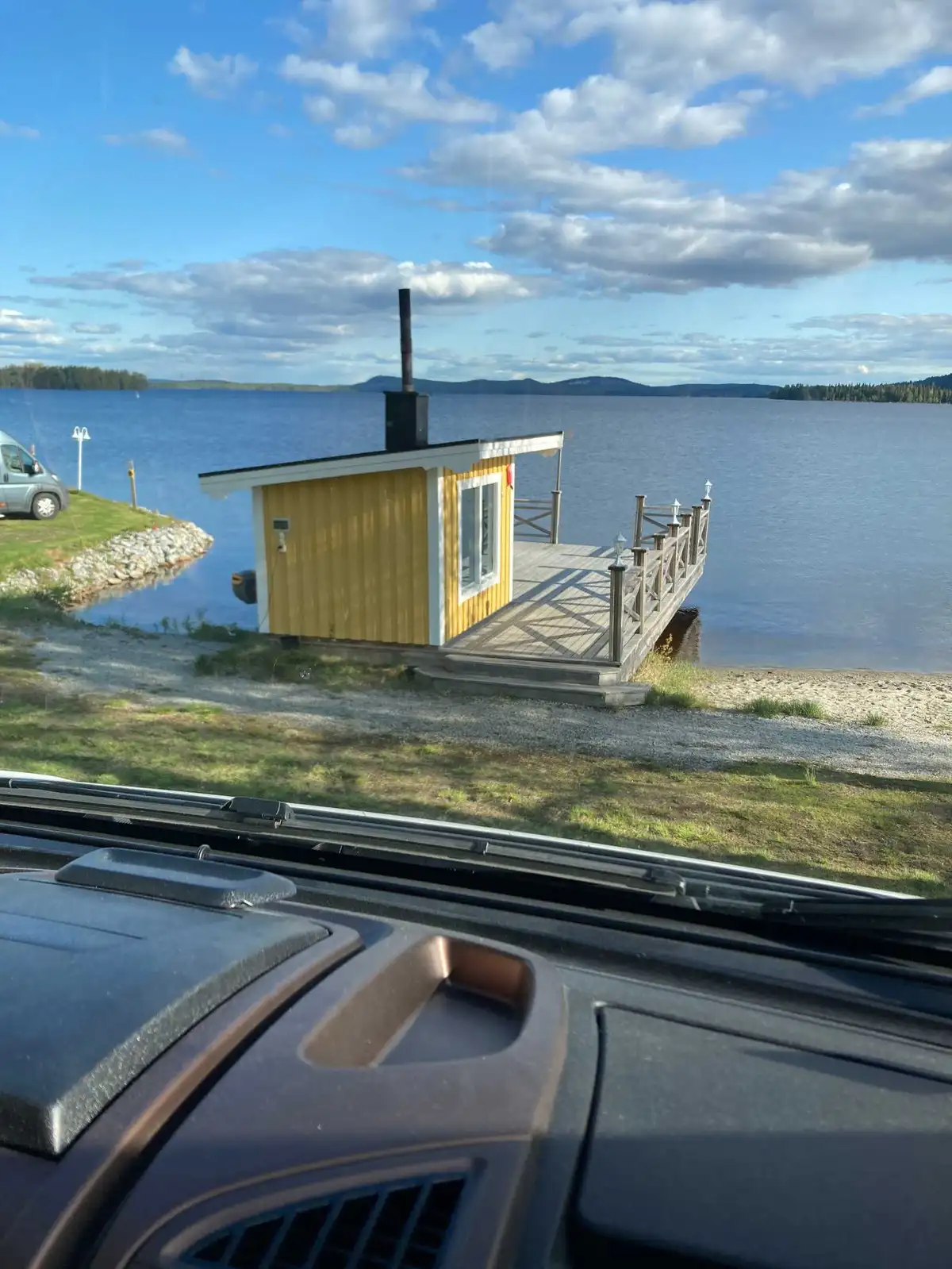 En rofylld kustlandskap med en sjö vid Kolgårdens stugby & camping, där himlen är täckt av moln.