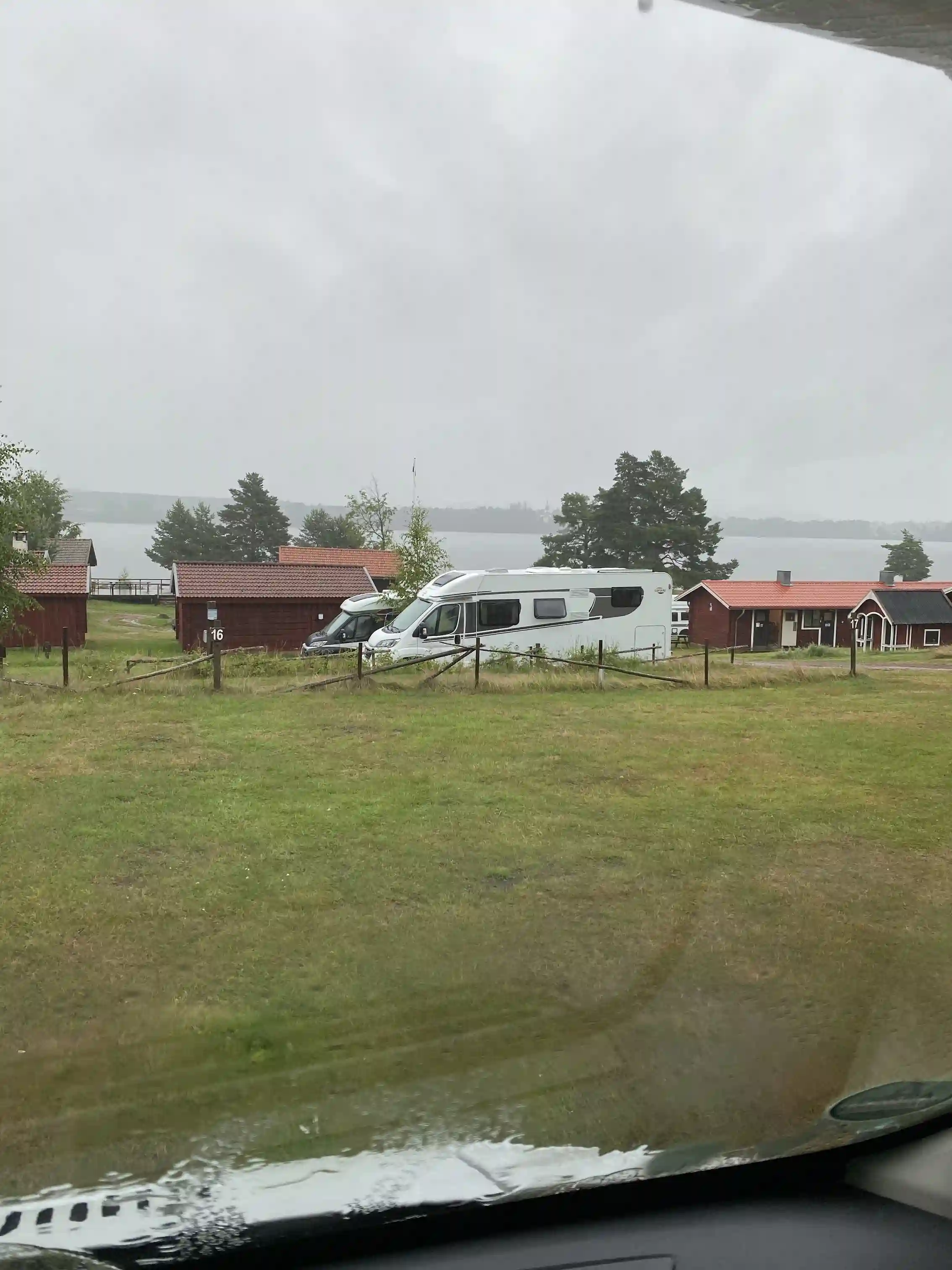 En parkeringsplats vid Västanviksbadets camping i Leksand, med flera bilar parkerade under en molnig himmel.