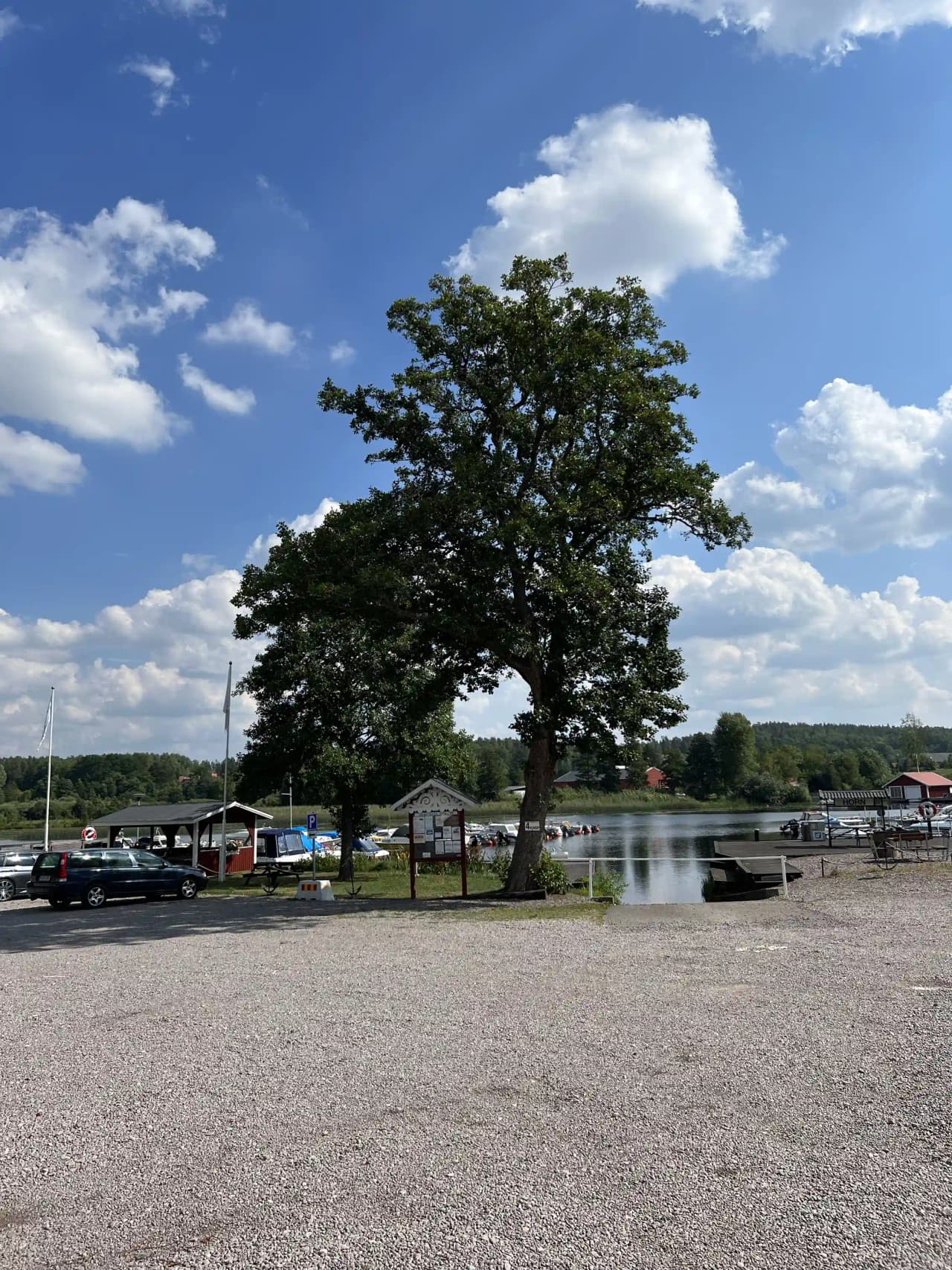 En parkering nära södra Kinda Båtklubb, med parkerade lastbilar i skuggan av stora cumulusmoln på himlen och grönskande omgivningar i Lake District.