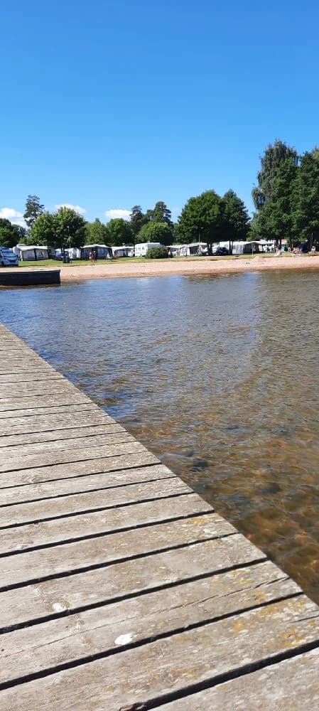 En solig sommardag vid en blå vattensjö med klar horisont.