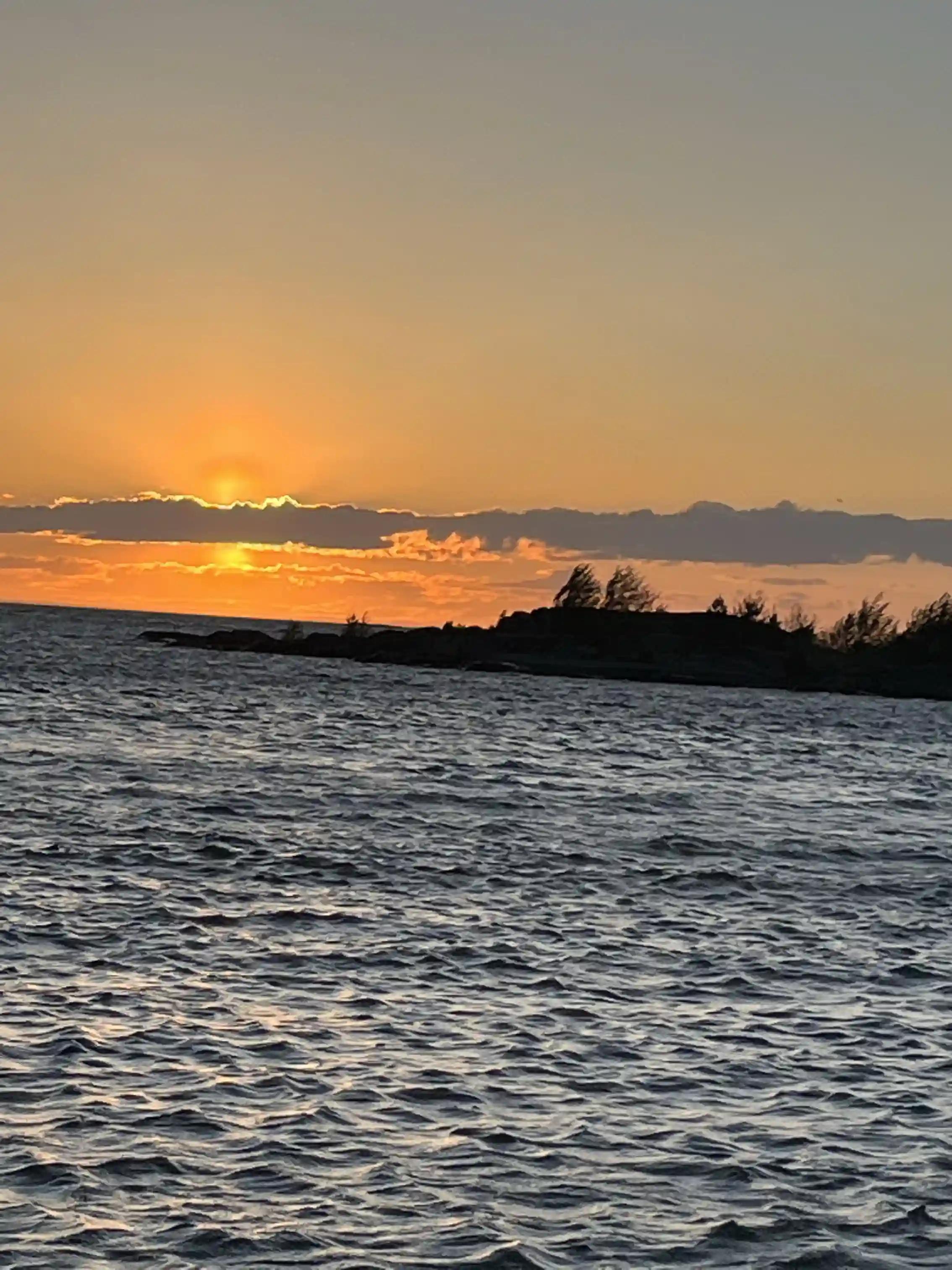 En solnedgång över Filsbäcks camping med himlen och horisonten reflekterade i det stilla vattnet. Moln syns svagt mot den efterglödande himlen.