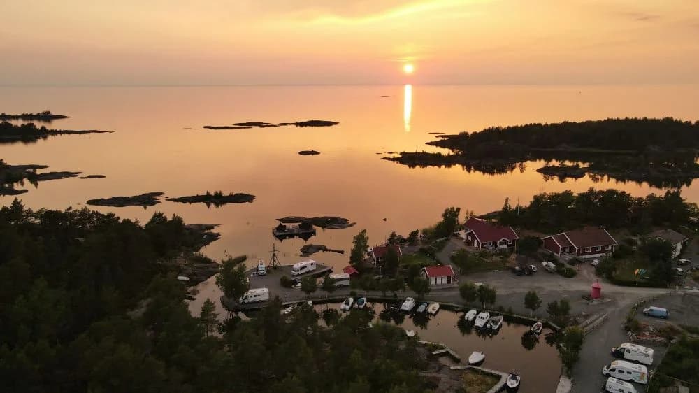 En stillsam solnedgång vid Filsbäcks camping visar kustlinjen med en sjö som speglar kvällshimlens mjuka färger.