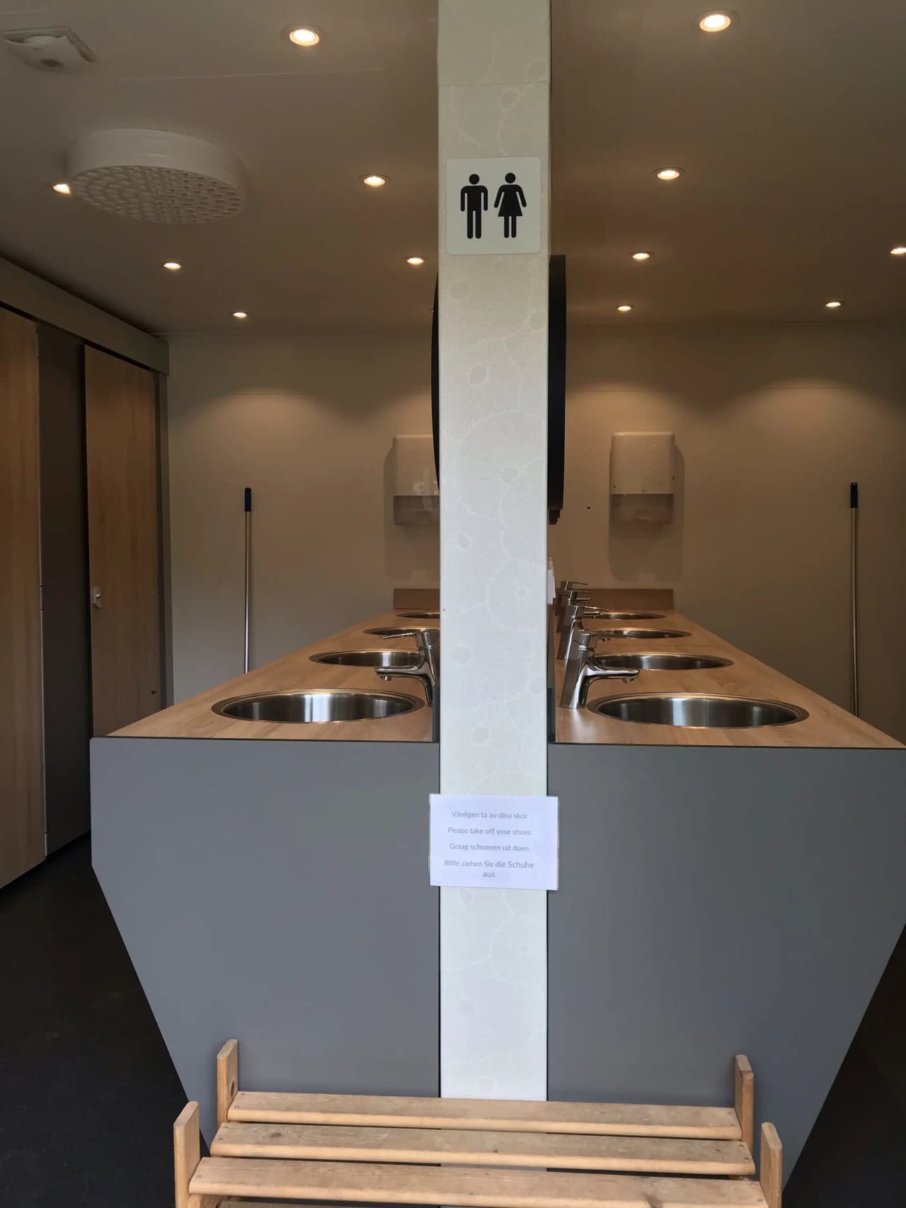 Bild av en interiör på Våmåbadets camping, med träinredning och trägolv. Taket har träpaneler och rummet är dekorerat med moderna ljusarmaturer i silver. Designen ger en rustik och inbjudande känsla.