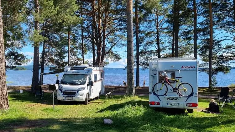 En campingplats vid kusten med flera husbilar och husvagnar parkerade nära en strand.