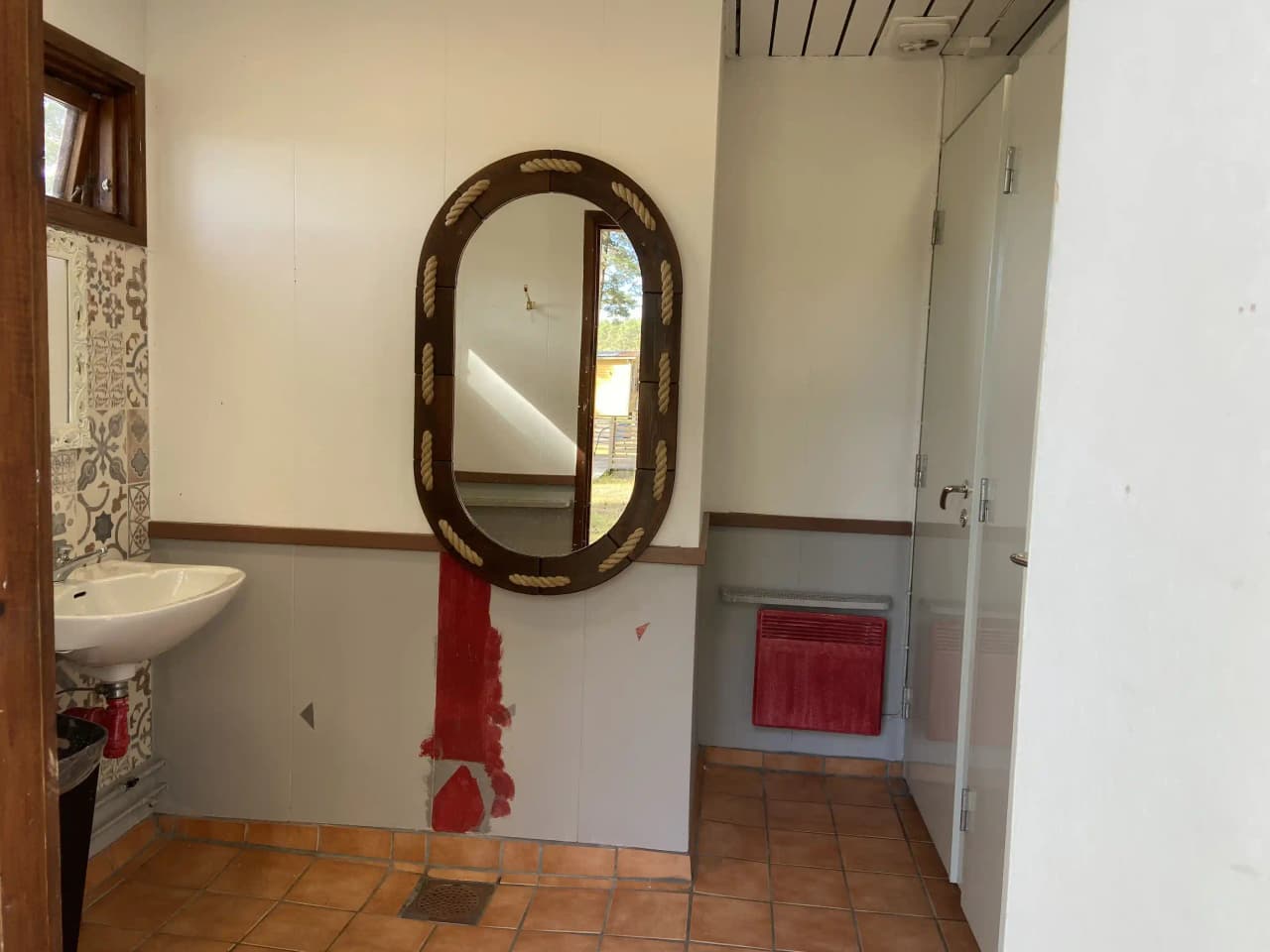 En modern campingtoalett med trägolv, trämöbler och kaklade väggar, utrustad med en spegel och VVS-armaturer.