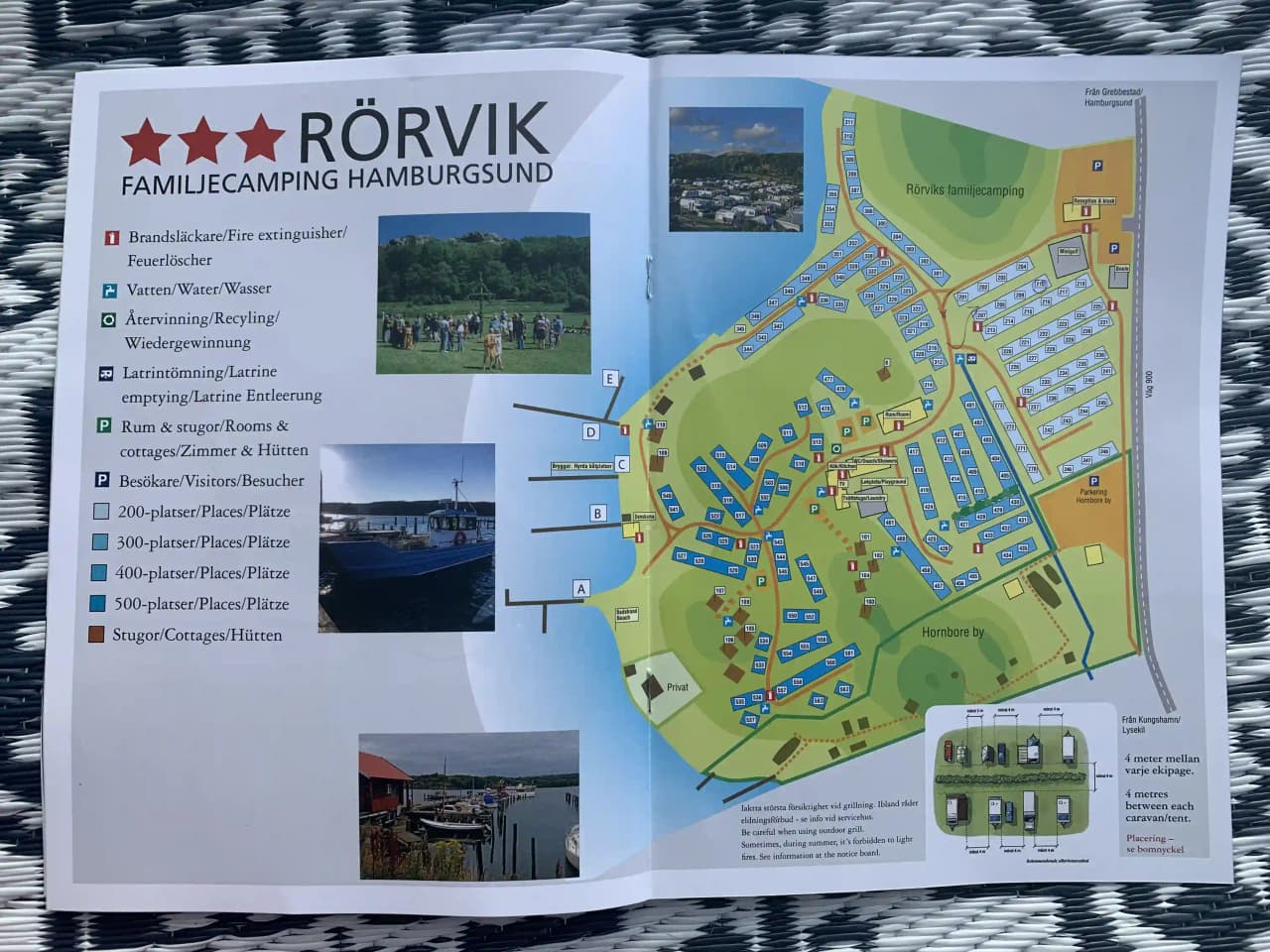 Flygbild över Rörviks Camping visar en kustnära anläggning med campingplatser och grönområden intill en bukt. Området omges av naturskön miljö, perfekt för avkoppling och rekreation.