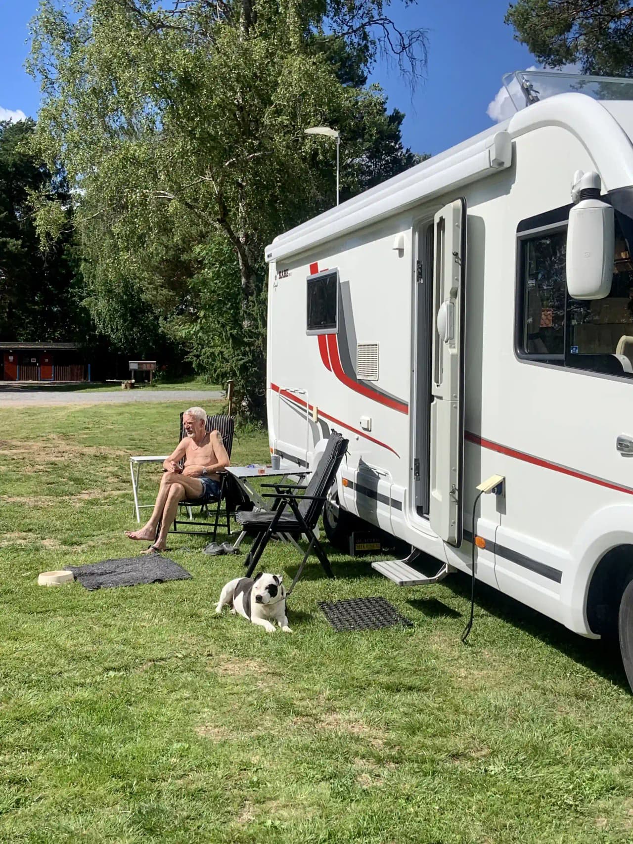 En campingplats med en husvagn och grön gräsmatta, där flera cyklar står parkerade.