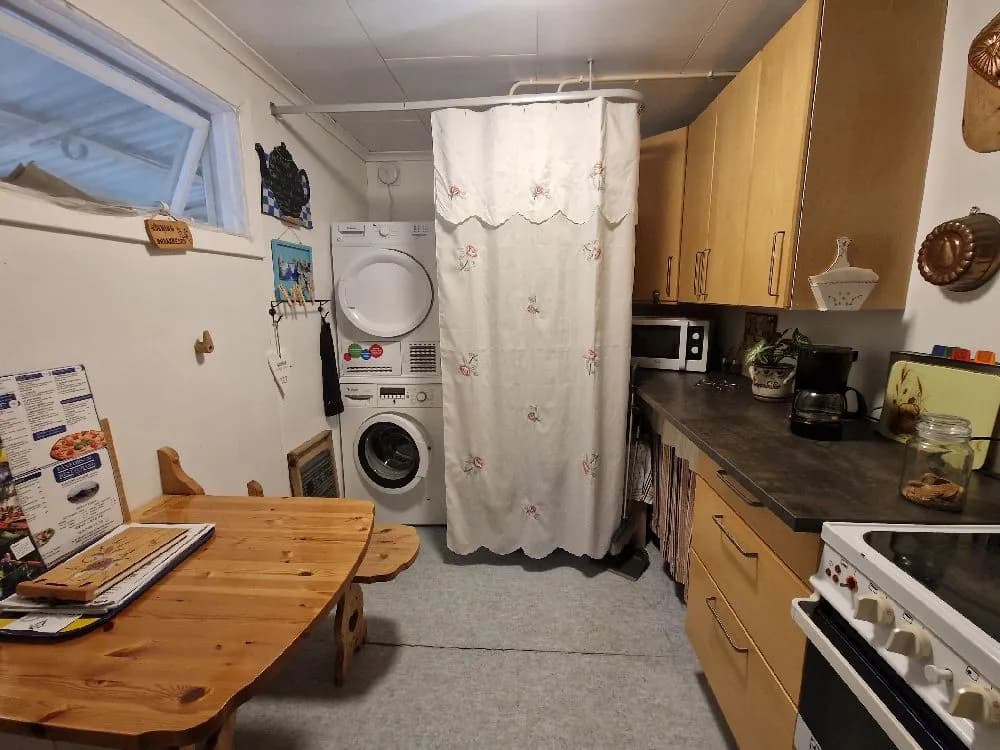 En ljus och välorganiserad tvättstuga med träelement, utrustad med flera tvättmaskiner och torktumlare. Golvet är täckt med ljust material, och belysningen bidrar till en trivsam atmosfär.