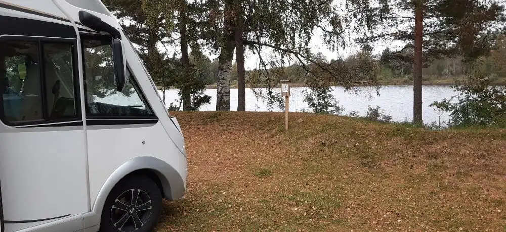 En husvagn står parkerad på en campingplats omgiven av grönska.