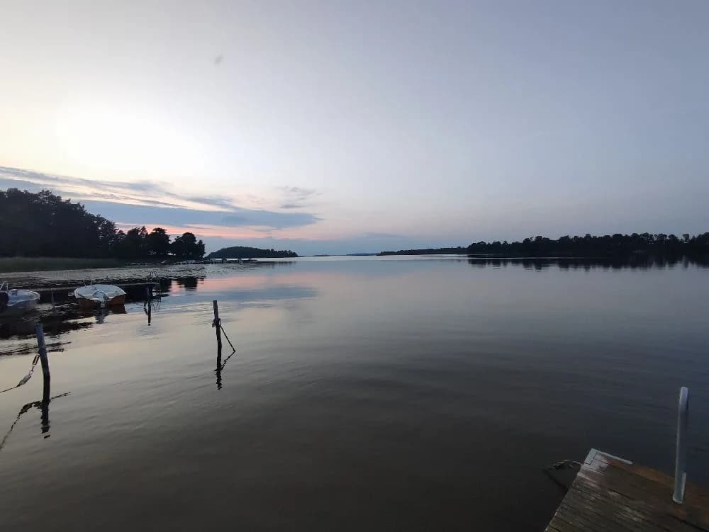 En lugn kvällsvy vid en vattensamling på Parken Zoo Camping och Stugby, med speglingar i vattnet och en himmel i skymningsljus i bakgrunden.