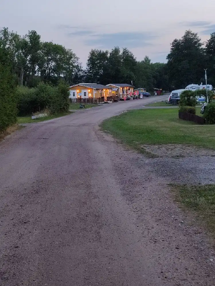 En bild på ett parkområde vid Parken Zoo Camping och Stugby med flera husbilar och husvagnar parkerade på grusade platser.