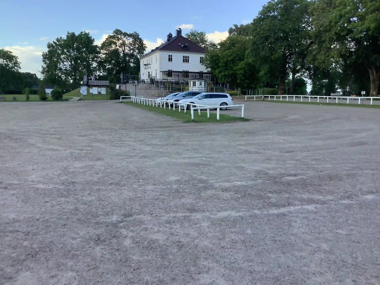 En sport utility vehicle parkerad framför Hofsnäs Herrgård på en solig dag. Herrgården syns i bakgrunden med grönska runt omkring.