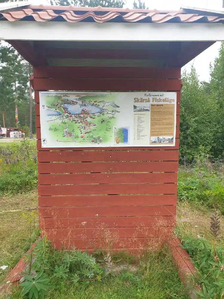 En naturskön campingplats med grönskande fält och jordig terräng i Skärså, omgiven av öppna ängar och klarblå himmel. Perfekt för naturälskare och friluftsliv.