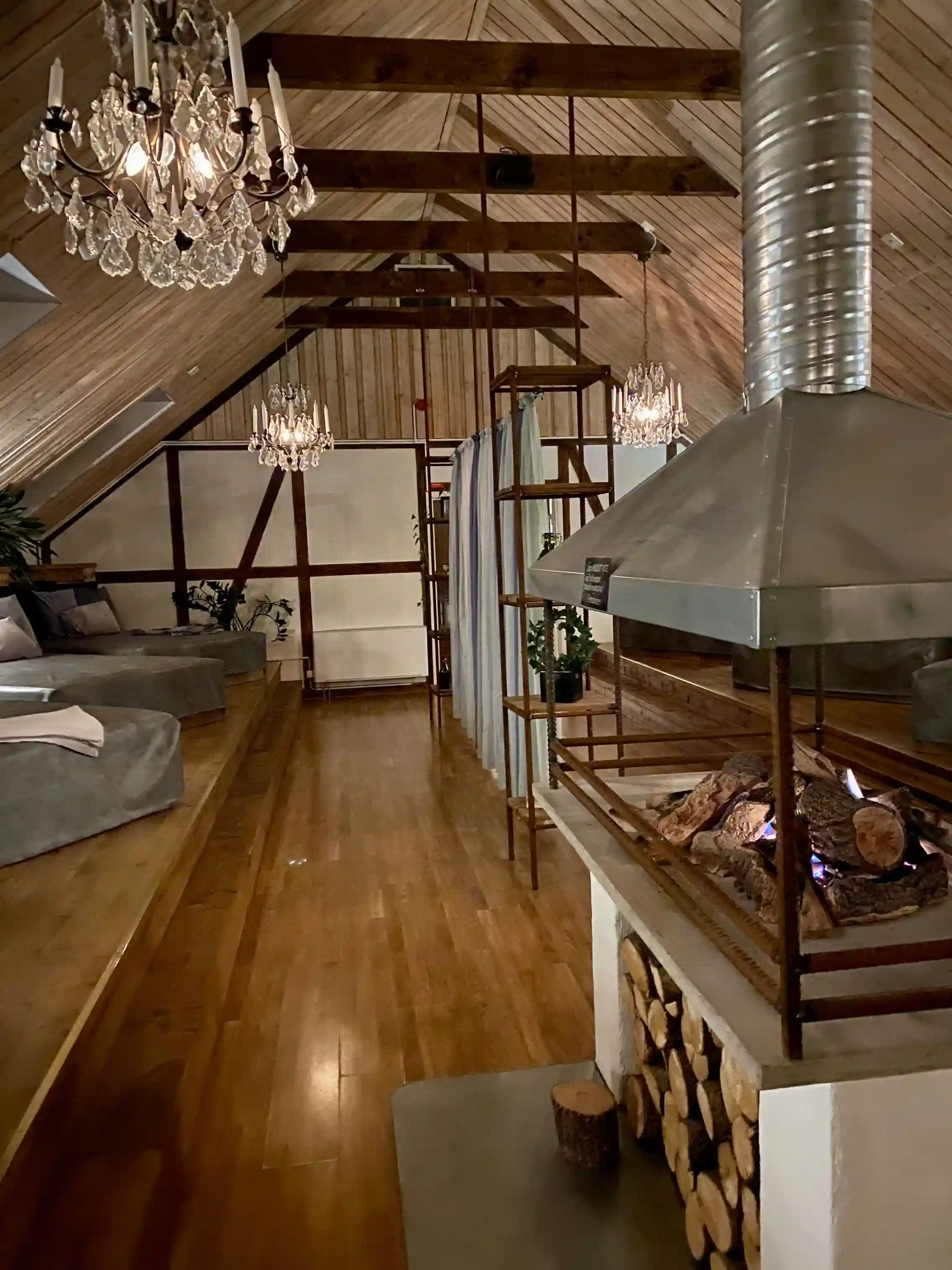 Bild av en elegant inredd interiör på Hotell & Spa Lögnäs Gård, med trädetaljer i taket, smakfull belysning och en stilig ljuskrona som hänger centralt. Golvet är av trä, och möblerna harmoniserar med det rustika men moderna designkonceptet.