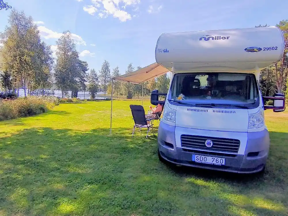 En husbil parkerad framför Moarps B&B, omgiven av grönska.