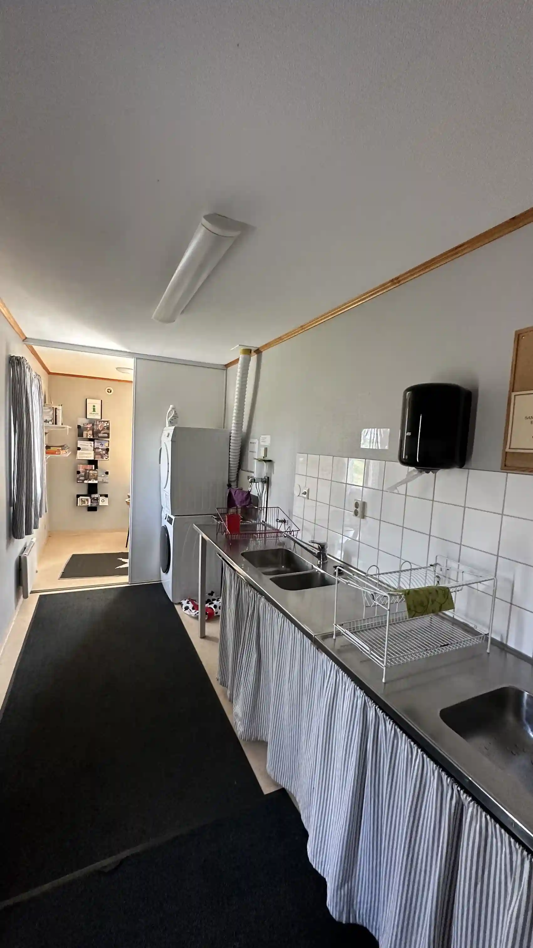 En mysig inomhusmiljö på Hoks naturcamping med trägolv och trädetaljer i taket. Rum med enkel belysning och bekväma möbler för en avkopplande vistelse.