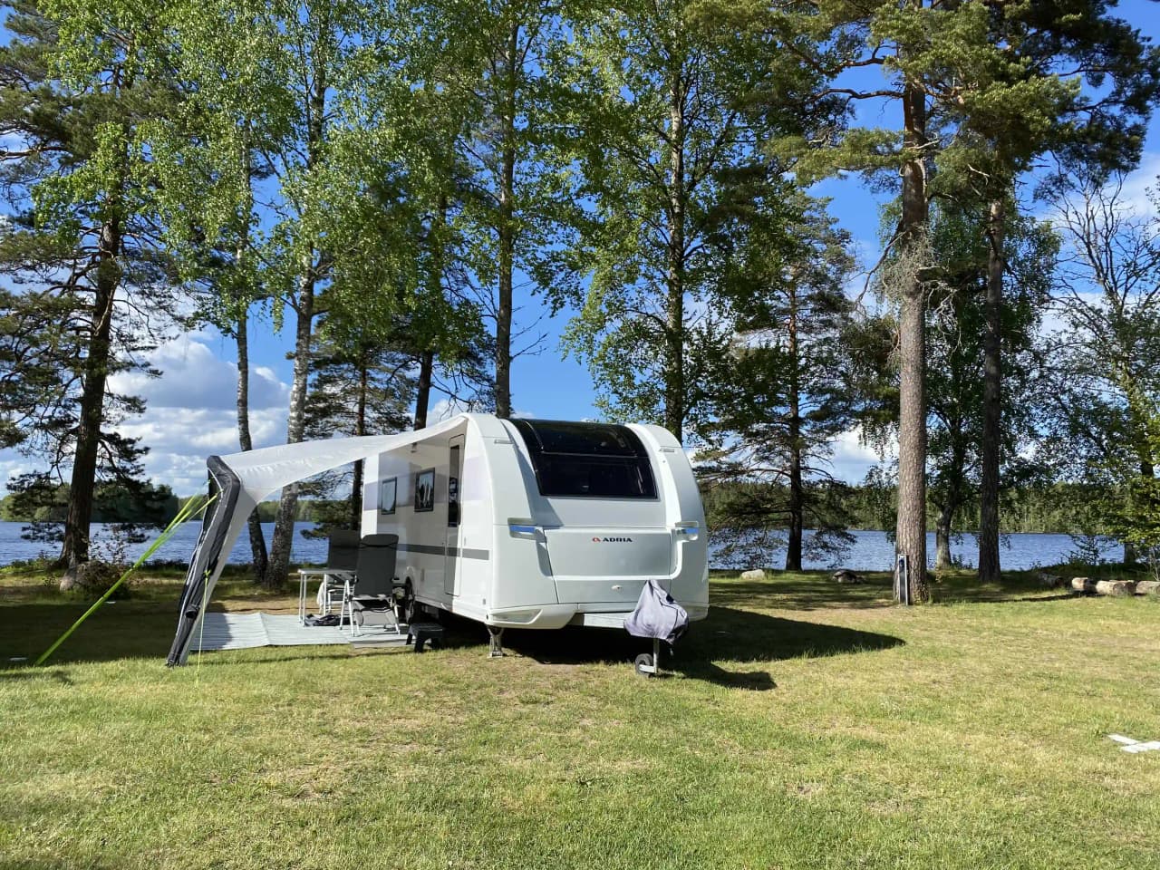 En husvagn och en husbil parkerade på Orrefors camping, omgivna av grönska och en lugn atmosfär.