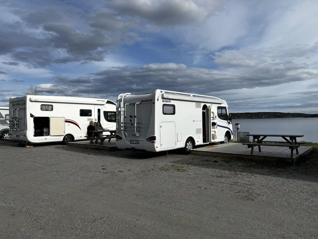 En parkering vid Arvika småbåtshamn med flera husbilar och transportfordon i bakgrunden.